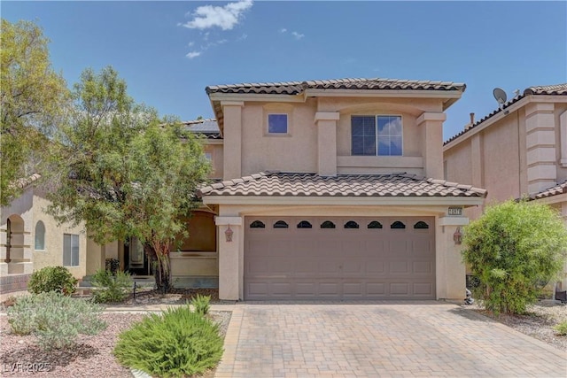 10978 Dornoch Castle St, Las Vegas, NV 89141 - mediterranean / spanish house featuring a tile roof, an attached garage, stucco siding, and decorative driveway