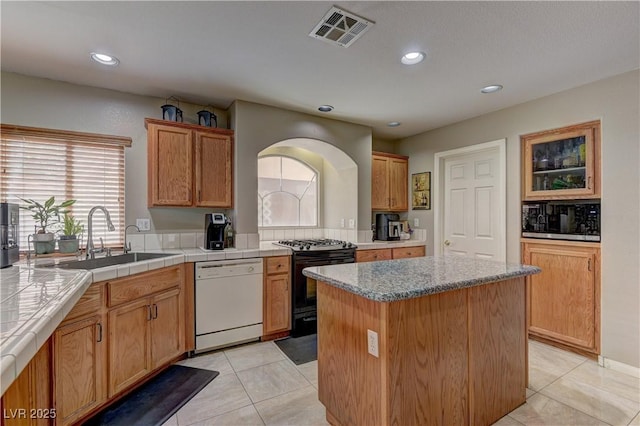 10978 Dornoch Castle St, Las Vegas, NV 89141 - kitchen featuring white dishwasher, black gas range, built in microwave, a center island, and light tile patterned flooring