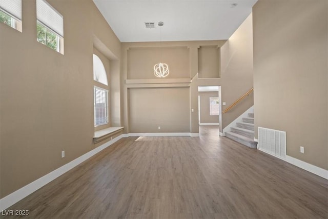 9794 Ice Box Canyon Ct, Las Vegas, NV 89117 - unfurnished living room with wood finished floors, stairs, a high ceiling, and a chandelier