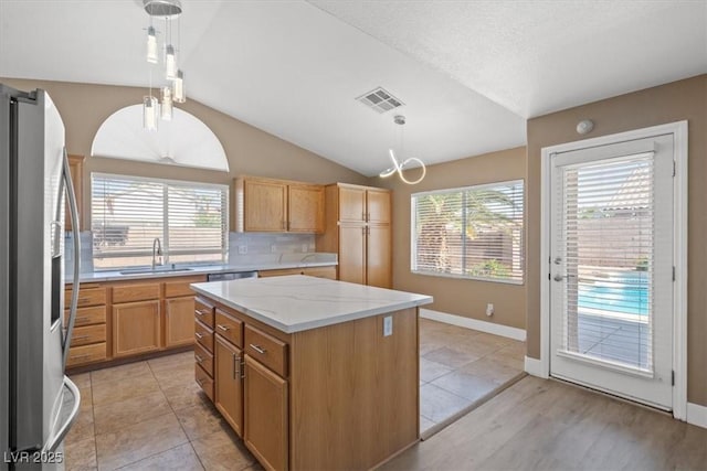 9794 Ice Box Canyon Ct, Las Vegas, NV 89117 - kitchen featuring appliances with stainless steel finishes, vaulted ceiling, plenty of natural light, a center island, and hanging light fixtures