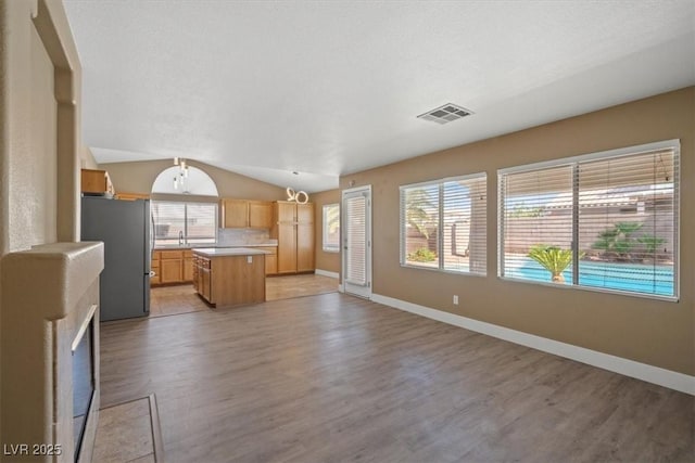 9794 Ice Box Canyon Ct, Las Vegas, NV 89117 - kitchen with freestanding refrigerator, light wood finished floors, open floor plan, a kitchen island, and light countertops