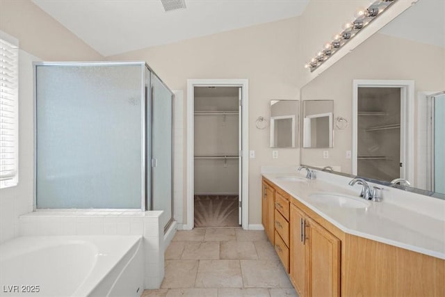 9794 Ice Box Canyon Ct, Las Vegas, NV 89117 - full bathroom featuring a walk in closet, a stall shower, double vanity, a bath, and vaulted ceiling