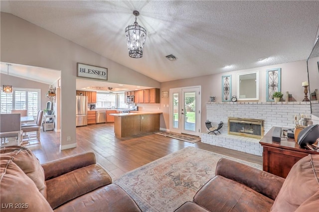 1605 Siboney Dr, Las Vegas, NV 89123 - living area with lofted ceiling, a chandelier, wood finished floors, a fireplace, and a textured ceiling