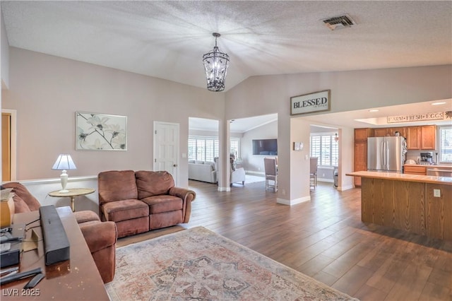 1605 Siboney Dr, Las Vegas, NV 89123 - living room featuring lofted ceiling, dark wood-type flooring, a chandelier, and a textured ceiling