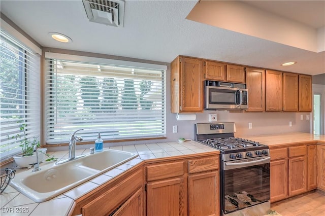 1605 Siboney Dr, Las Vegas, NV 89123 - kitchen featuring stainless steel appliances, tile counters, recessed lighting, and brown cabinetry