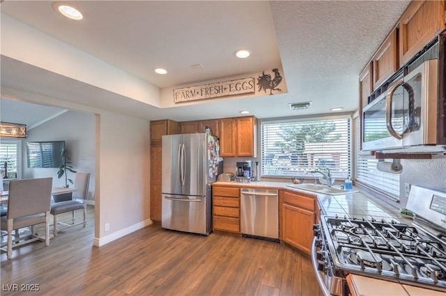 1605 Siboney Dr, Las Vegas, NV 89123 - kitchen with appliances with stainless steel finishes, dark wood-type flooring, brown cabinets, a raised ceiling, and recessed lighting