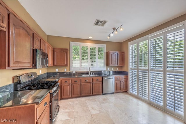 233 Ventana Heights St, Henderson, NV 89074 - kitchen with appliances with stainless steel finishes, brown cabinetry, healthy amount of natural light, and light tile patterned flooring