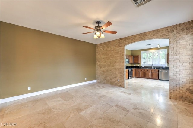 233 Ventana Heights St, Henderson, NV 89074 - unfurnished living room featuring a ceiling fan, arched walkways, light tile patterned floors, and brick wall