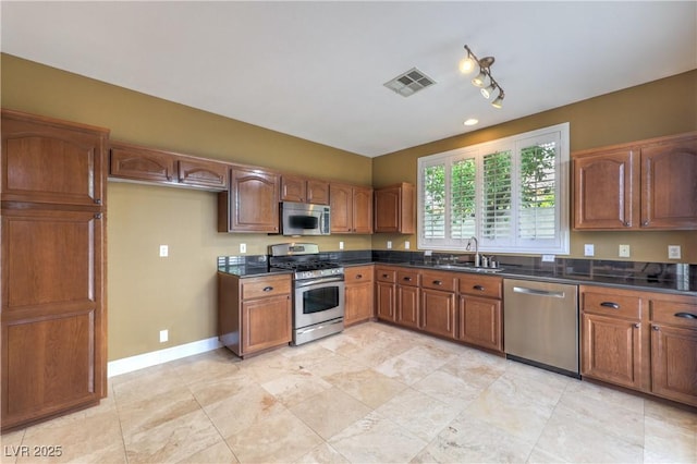 233 Ventana Heights St, Henderson, NV 89074 - kitchen featuring appliances with stainless steel finishes, dark countertops, and brown cabinetry