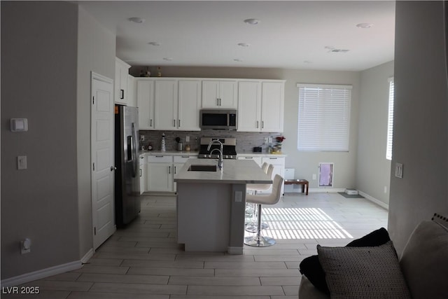 7022 Judith River St, North Las Vegas, NV 89084 - kitchen featuring appliances with stainless steel finishes, wood tiled floors, tasteful backsplash, a kitchen bar, and light countertops