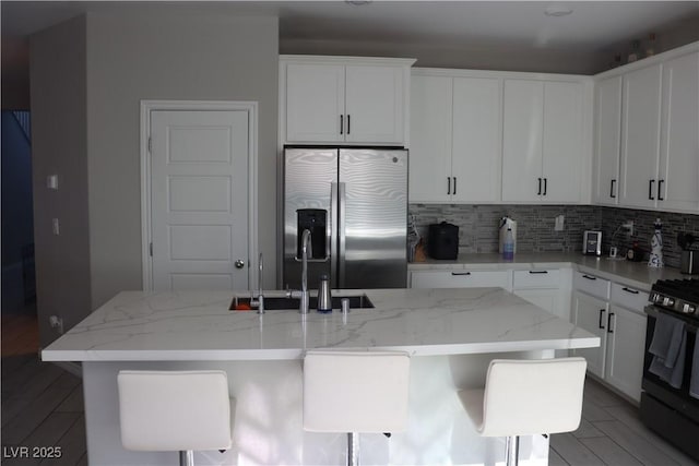 7022 Judith River St, North Las Vegas, NV 89084 - kitchen with stainless steel fridge, gas range, backsplash, a kitchen island with sink, and light stone countertops