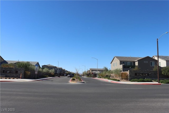 7022 Judith River St, North Las Vegas, NV 89084 - view of asphalt road featuring sidewalks, street lights, a residential view, and curbs