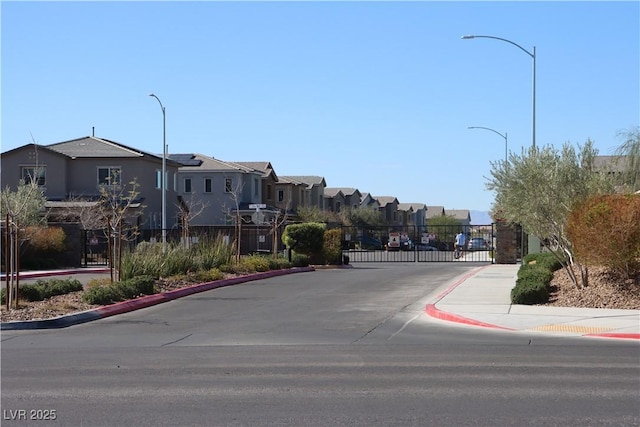 7022 Judith River St, North Las Vegas, NV 89084 - view of asphalt road featuring a residential view, curbs, street lights, sidewalks, and a gate