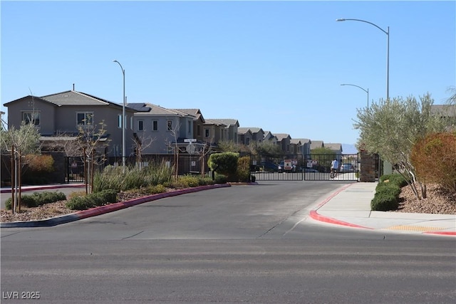 7022 Judith River St, North Las Vegas, NV 89084 - view of asphalt road featuring a residential view, curbs, street lights, a gate, and sidewalks