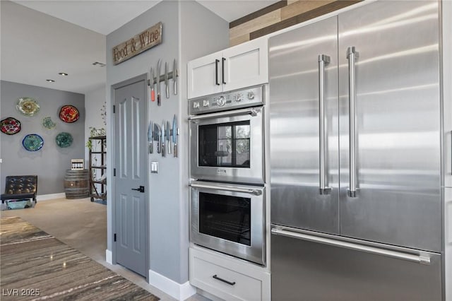 10596 Refugio St, Las Vegas, NV 89141 - kitchen with appliances with stainless steel finishes, white cabinets, light colored carpet, and stone countertops