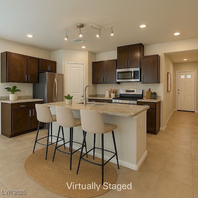 4441 Glossier Ave, North Las Vegas, NV 89084 - kitchen featuring appliances with stainless steel finishes, light tile patterned flooring, dark brown cabinets, a breakfast bar, and recessed lighting