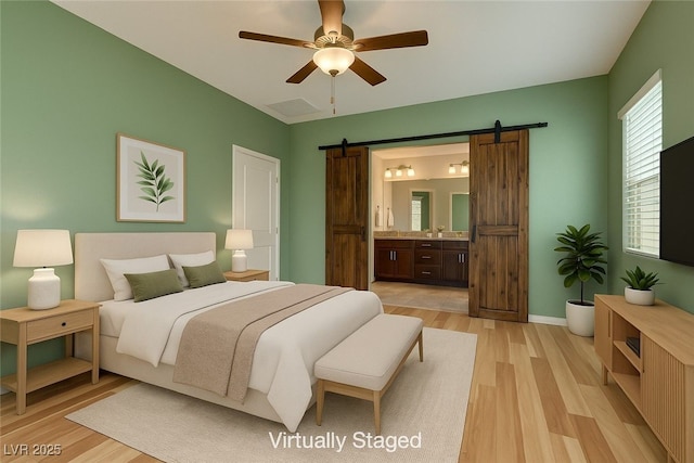 4441 Glossier Ave, North Las Vegas, NV 89084 - bedroom featuring a barn door, light wood-style floors, ensuite bathroom, and ceiling fan