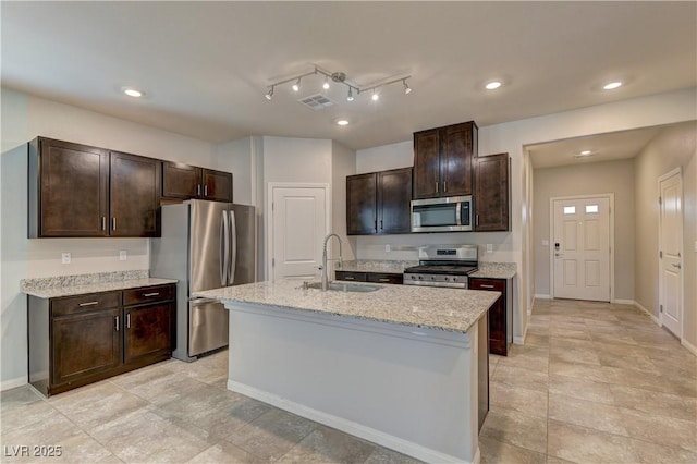 4441 Glossier Ave, North Las Vegas, NV 89084 - kitchen featuring appliances with stainless steel finishes, dark brown cabinets, recessed lighting, a center island with sink, and light stone counters