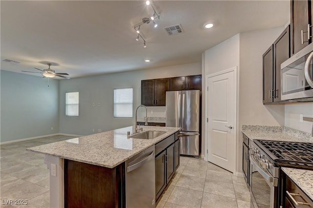 4441 Glossier Ave, North Las Vegas, NV 89084 - kitchen with stainless steel appliances, dark brown cabinets, ceiling fan, a center island with sink, and light stone countertops