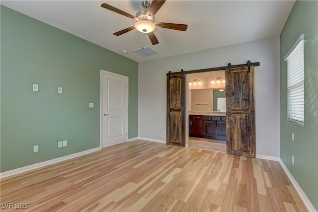 4441 Glossier Ave, North Las Vegas, NV 89084 - unfurnished room with a barn door, light wood finished floors, and ceiling fan