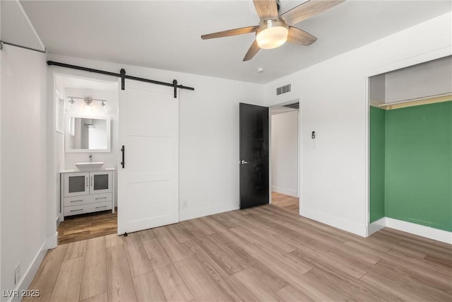 1915 Balboa Ave, Las Vegas, NV 89169 - unfurnished bedroom featuring light wood-type flooring, a barn door, and a ceiling fan