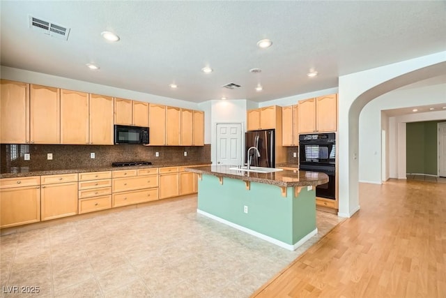 262 Pebble Canyon Dr, Las Vegas, NV 89123 - kitchen with light brown cabinetry, black appliances, arched walkways, tasteful backsplash, and a kitchen bar