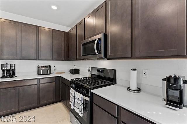 10106 Queens Pearl St, Las Vegas, NV 89141 - kitchen with gas range, stainless steel microwave, light countertops, dark brown cabinetry, and light tile patterned floors