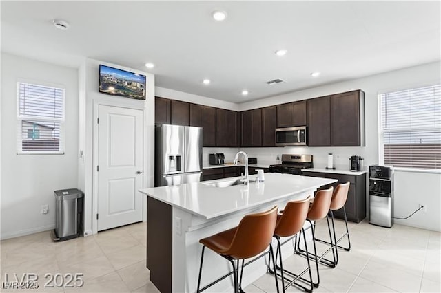10106 Queens Pearl St, Las Vegas, NV 89141 - kitchen with stainless steel appliances, a breakfast bar, dark brown cabinetry, light countertops, and a center island with sink