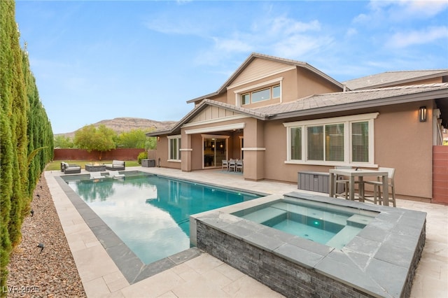 5676 Corona Vista St, Las Vegas, NV 89135 - rear view of property with an in-ground hot tub, stucco siding, a patio, a fenced backyard, and a mountain view