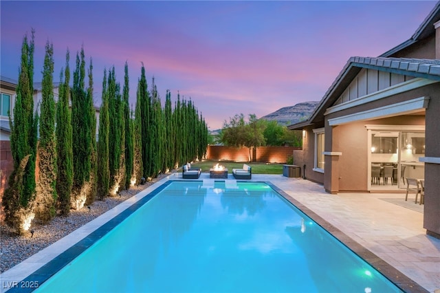 5676 Corona Vista St, Las Vegas, NV 89135 - pool at dusk featuring a patio area, a fenced backyard, and an outdoor fire pit