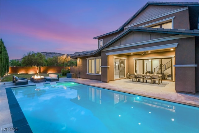 5676 Corona Vista St, Las Vegas, NV 89135 - pool at dusk featuring an outdoor fire pit, a patio, a fenced backyard, and a ceiling fan