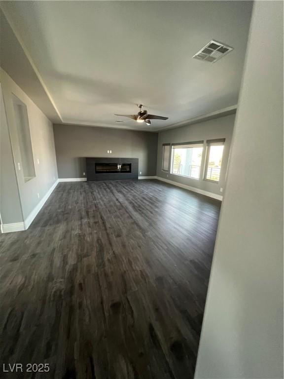 8094 Noble Ridge St, Las Vegas, NV 89139 - unfurnished living room featuring a ceiling fan, dark wood finished floors, and a glass covered fireplace