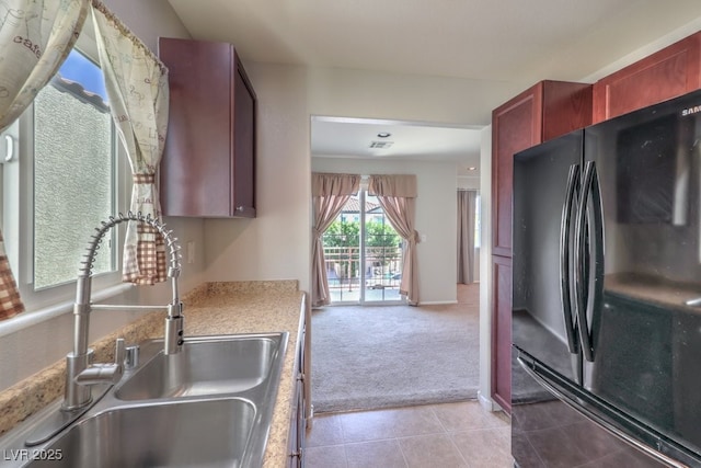 9065 Tantalizing Ave, Las Vegas, NV 89149 - kitchen featuring freestanding refrigerator, light carpet, light countertops, light tile patterned floors, and reddish brown cabinets