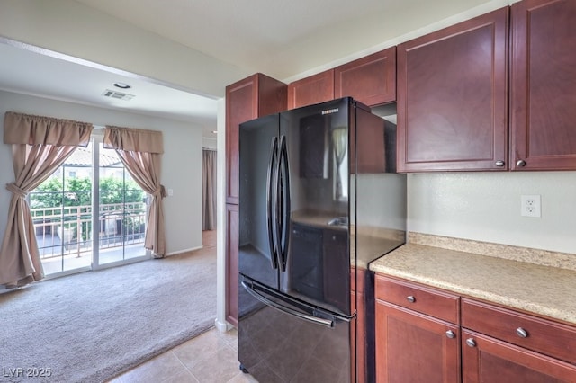 9065 Tantalizing Ave, Las Vegas, NV 89149 - kitchen with freestanding refrigerator, light carpet, reddish brown cabinets, and light countertops