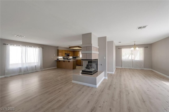 5204 Padua Way, Las Vegas, NV 89107 - unfurnished living room with a chandelier, light wood-style floors, and a tiled fireplace