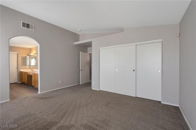 5204 Padua Way, Las Vegas, NV 89107 - unfurnished bedroom with carpet floors, a closet, arched walkways, connected bathroom, and lofted ceiling