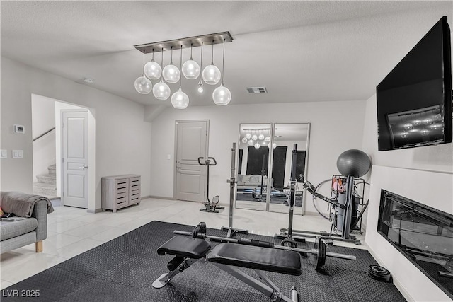 8089 Misty Canyon Ave, Las Vegas, NV 89113 - workout area with a glass covered fireplace, tile patterned floors, and a chandelier