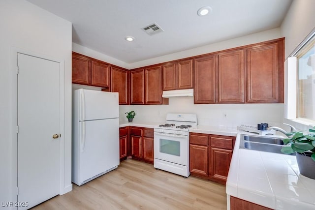 5013 Diamond Ranch Ave, Las Vegas, NV 89131 - kitchen with white appliances, under cabinet range hood, tile counters, light wood-type flooring, and recessed lighting