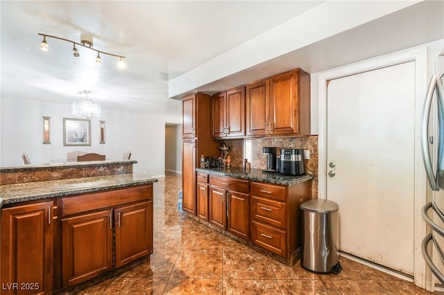 170 Palisade Ave, Las Vegas, NV 89110 - kitchen featuring dark countertops, backsplash, a chandelier, brown cabinets, and freestanding refrigerator