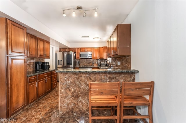 170 Palisade Ave, Las Vegas, NV 89110 - kitchen with stainless steel appliances, tasteful backsplash, a peninsula, and brown cabinetry