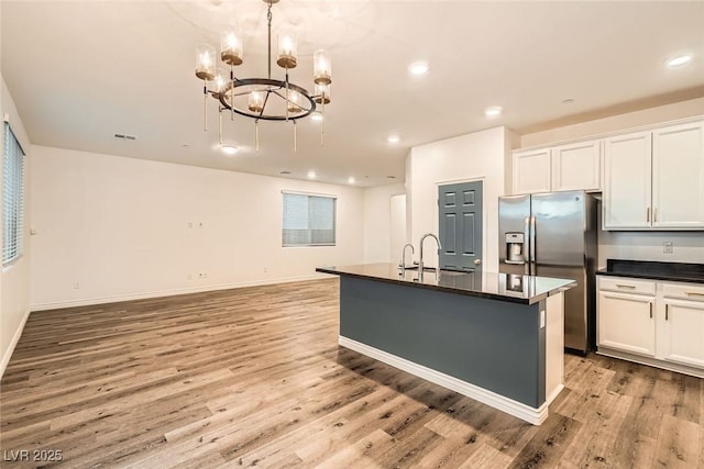 1009 Bluebell Brook St, Henderson, NV 89052 - kitchen with stainless steel fridge with ice dispenser, dark countertops, light wood finished floors, a chandelier, and recessed lighting