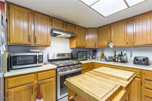 744 Milstead Ct, Las Vegas, NV 89110 - kitchen featuring stainless steel appliances, under cabinet range hood, wooden counters, brown cabinets, and tile patterned flooring