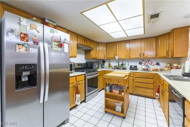 744 Milstead Ct, Las Vegas, NV 89110 - kitchen featuring appliances with stainless steel finishes, light countertops, light tile patterned flooring, brown cabinets, and under cabinet range hood