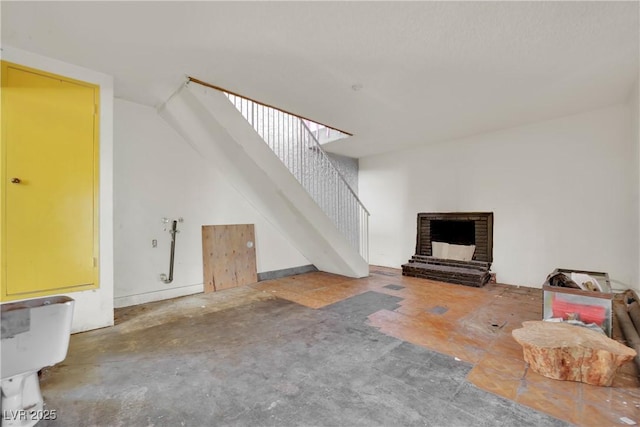 3009 Merritt Ave, Las Vegas, NV 89102 - unfurnished living room featuring stairway, a brick fireplace, and concrete flooring
