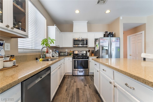 1014 Lone Pine River Ave, Henderson, NV 89002 - kitchen with stainless steel appliances, white cabinets, dark wood-style floors, light stone counters, and glass insert cabinets