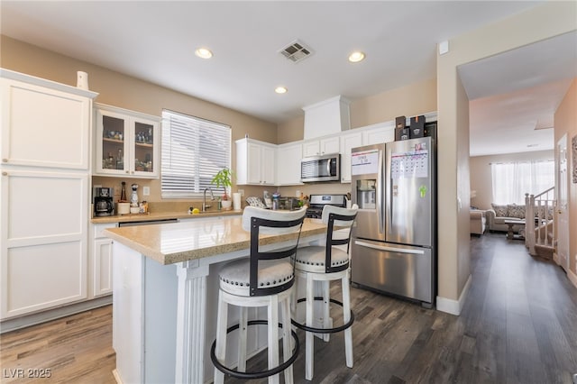 1014 Lone Pine River Ave, Henderson, NV 89002 - kitchen with stainless steel appliances, white cabinets, dark wood-style flooring, a breakfast bar, and a kitchen island
