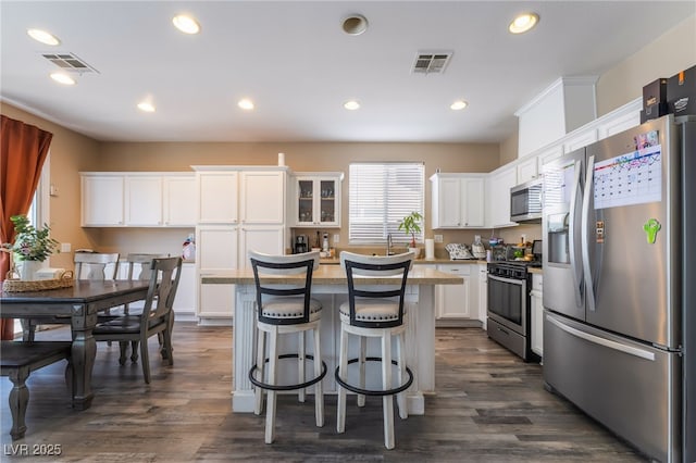1014 Lone Pine River Ave, Henderson, NV 89002 - kitchen featuring stainless steel appliances, white cabinetry, a kitchen bar, a kitchen island, and dark wood finished floors