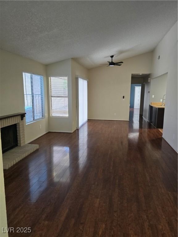123 Sirnoble St, Las Vegas, NV 89110 - unfurnished living room featuring wood finished floors, ceiling fan, healthy amount of natural light, a fireplace, and a textured ceiling