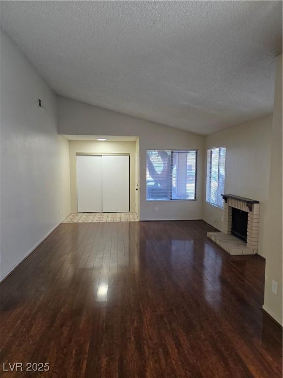 123 Sirnoble St, Las Vegas, NV 89110 - unfurnished living room with lofted ceiling, wood finished floors, a textured ceiling, and a brick fireplace