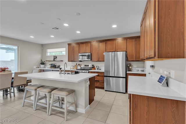 1309 Azure Jay Ave, North Las Vegas, NV 89084 - kitchen with appliances with stainless steel finishes, brown cabinetry, a breakfast bar, light tile patterned floors, and recessed lighting